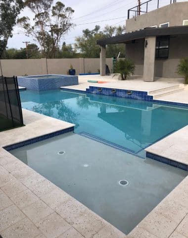 Modern backyard pool and raised spa with travertine decking